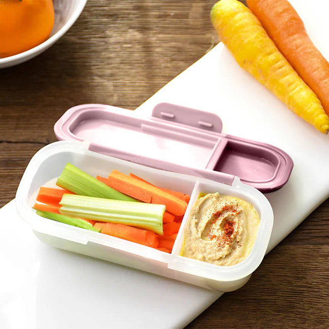 Bento box with vegetables and hummus on a wooden table