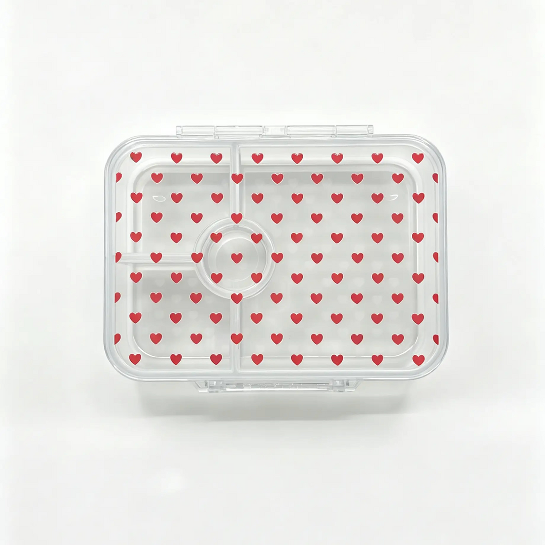 A clear plastic bento container with a lid patterned with small red hearts, shown from a top-down view on a white background.
