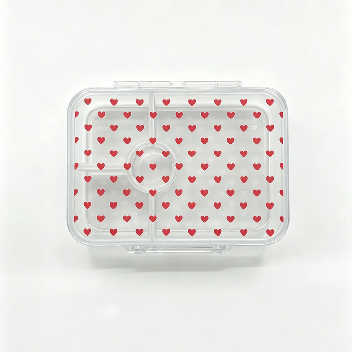 A clear plastic bento container with a lid patterned with small red hearts, shown from a top-down view on a white background.