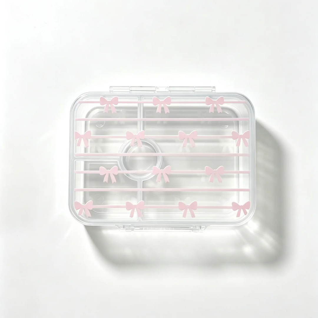 A clear plastic cosmetic organizer tray with a lid decorated with small pink bow patterns, shown on a clean white background with a soft shadow.