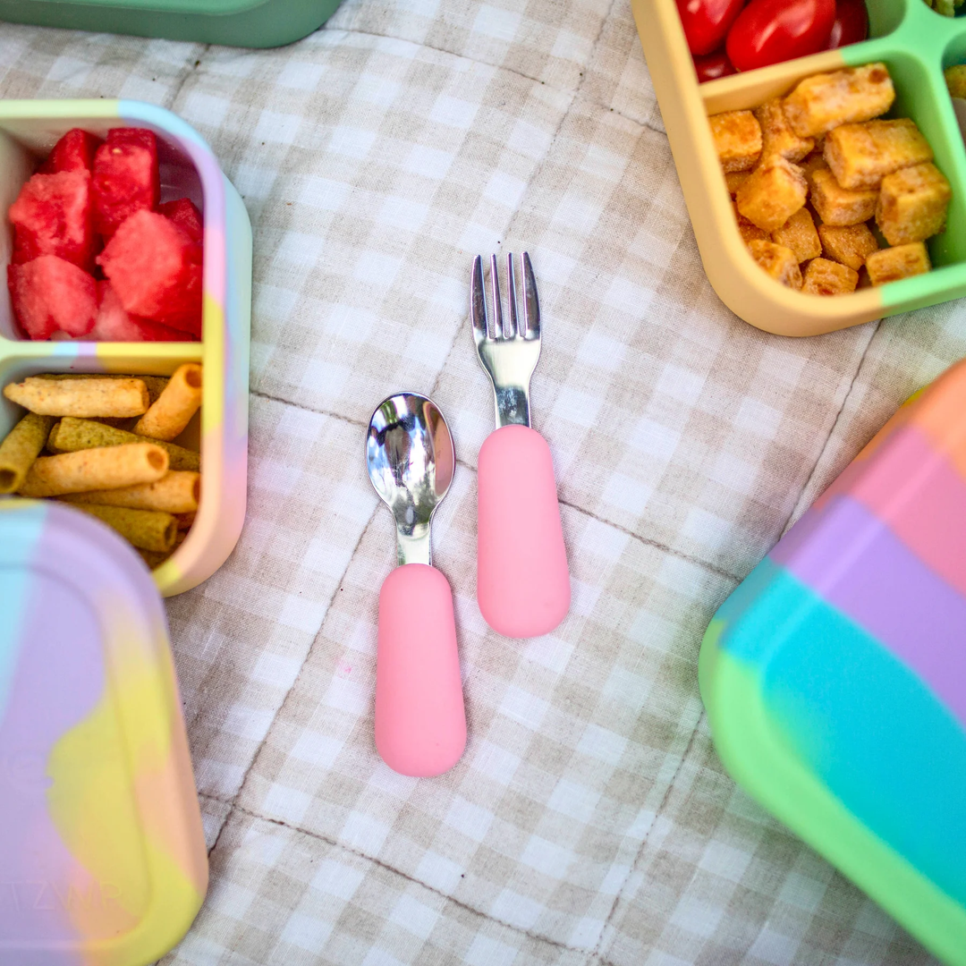 Colorful bento boxes with food and pink cutlery on a checkered tablecloth